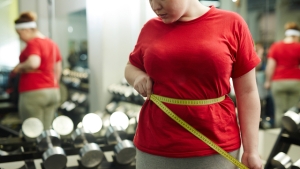Portrait,Of,Unrecognizable,Obese,Woman,Standing,Against,Mirror,In,Gym