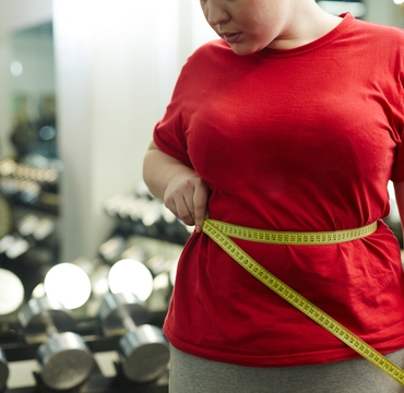 Portrait,Of,Unrecognizable,Obese,Woman,Standing,Against,Mirror,In,Gym