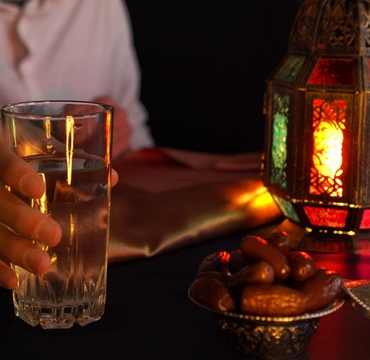 A young man prays and drinks water and eats dates. Evening meal during the Holy Muslim month of Ramadan
